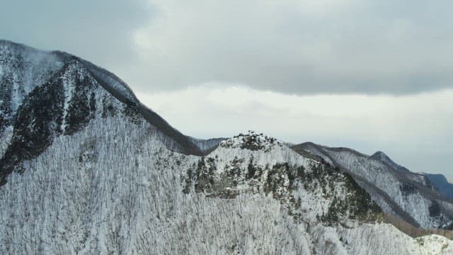 Snowy Mountain Peaks under Cloudy Sky