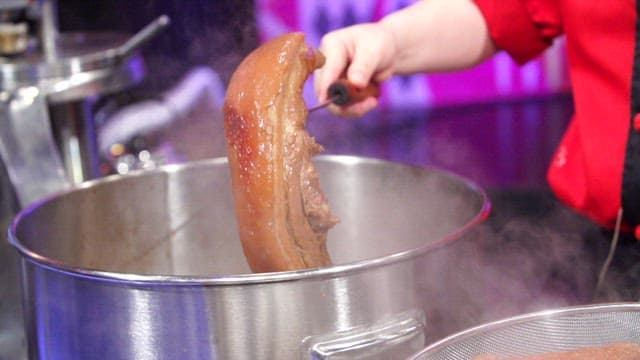 Chef preparing boiled pork slices in a kitchen