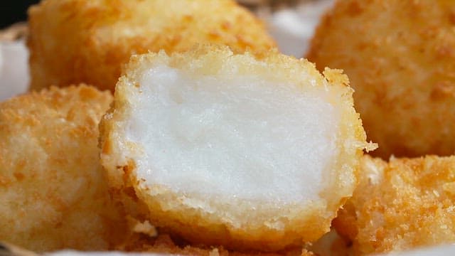 Pressing the crispy milk fritters with a fork