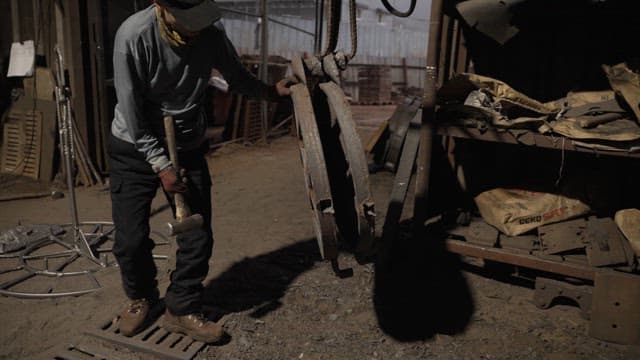 Worker handling heavy metal parts in a factory