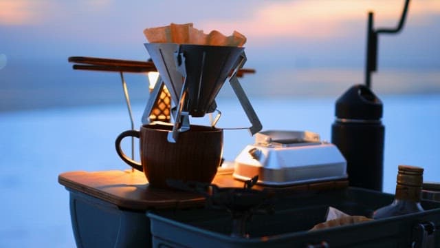 Preparing coffee on a portable setup during a sunset at the beach