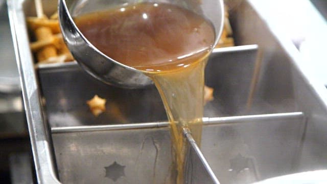 Pouring broth into a pot with fish cake skewers