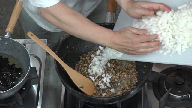 Adding Chopped Onions to the Frying Pan with Sizzling Minced Meat