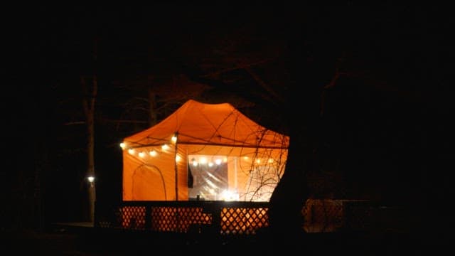 Brightly lit orange tent at night in a forest