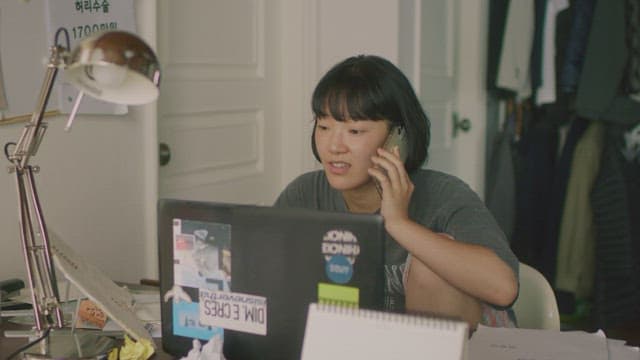 Woman answering phone call at desk with laptop