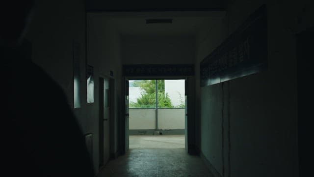 Two men walking through a dark hallway in a prison