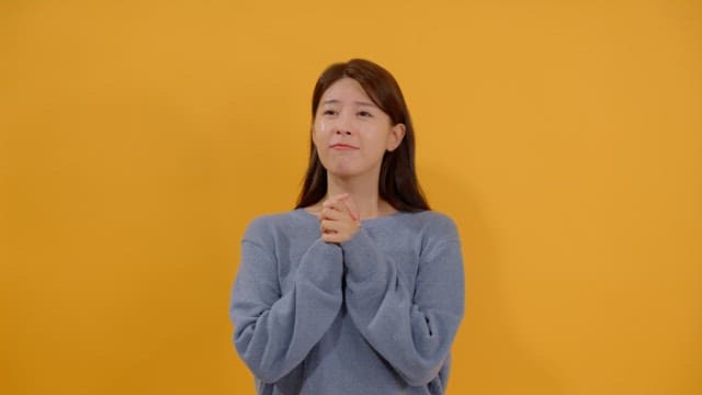 Woman praying with her hands together with a hopeful expression