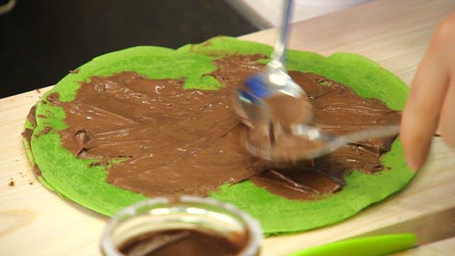 Spreading chocolate on a green crepe made with spinach