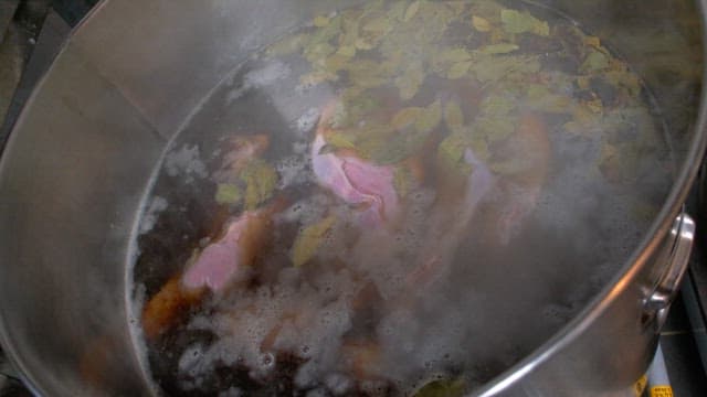 Large pot of meat and spices boiling on stove