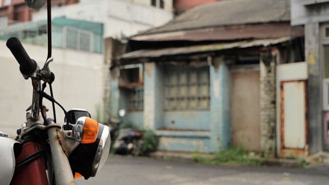Motorbike parked near an old, dilapidated building