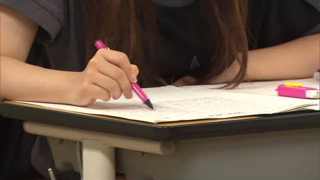 Student Solving Test Questions at Classroom Desk