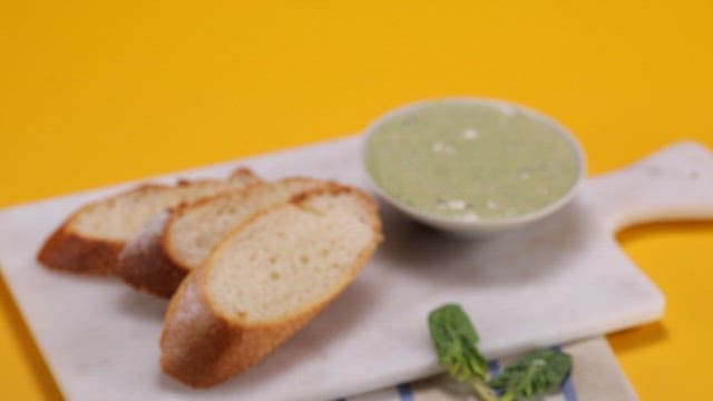 Slices of bread with green spinach dip on a board