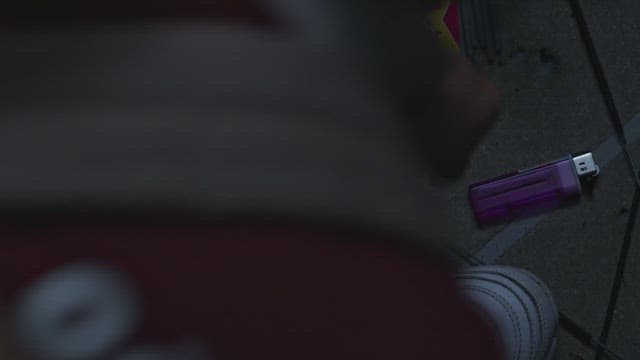 Examining a purple lighter on the street at night