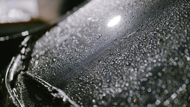 Rain droplets on a car hood and windscreen at night