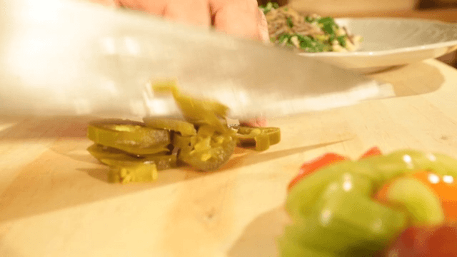 Chopping Jalapenos for Cooking on a Wooden Cutting Board