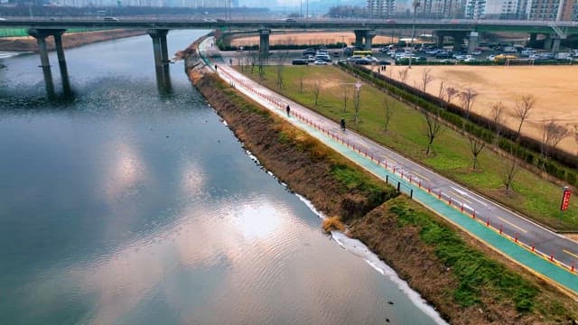 Riverside Pathway with People Walking and Bridge