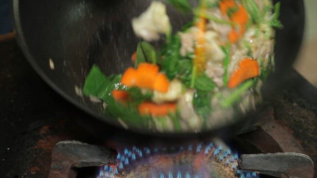 Vegetables and meat being stir-fried in a wok