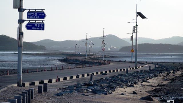 Car passing along a coastal road over mudflats exposed at low tide