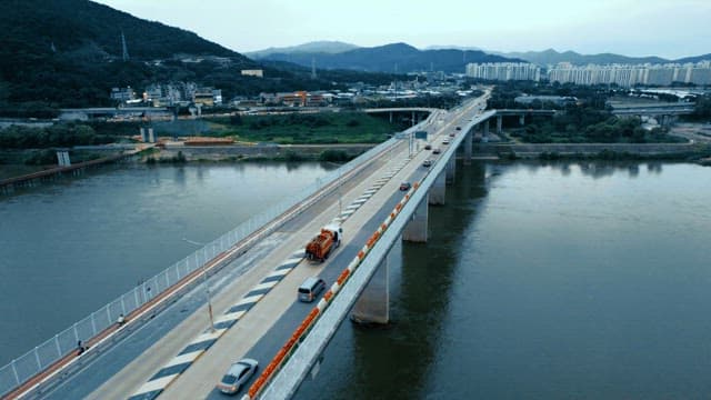Bridge with cars passing over a river with city skyline