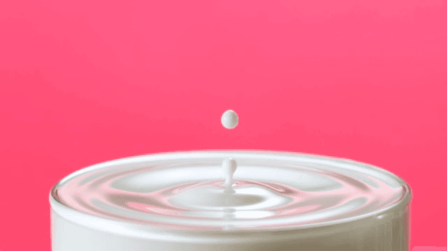 Milk drop creating ripples in a glass