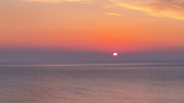 Calm sea under a red sunset sky