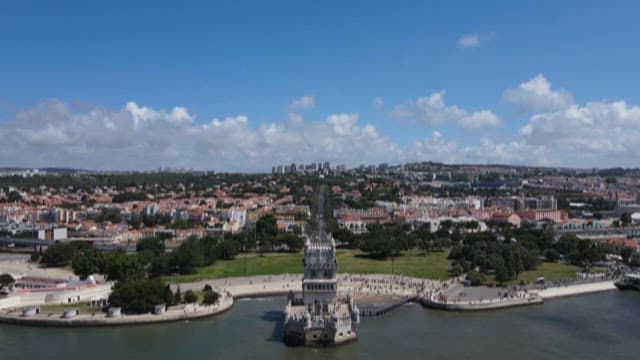 Clear Day View of Belém Tower by the Water with Tourists