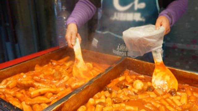 Merchant Serving Spicy Rice Cakes on Bowl
