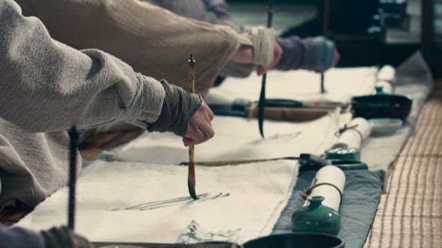 People painting on rice paper with a brush
