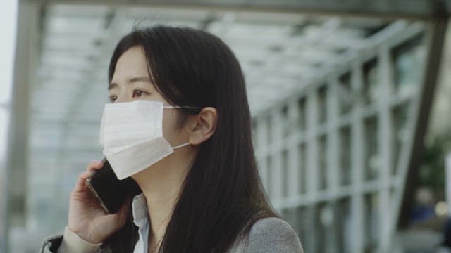 Woman in a mask talking on the phone outdoors