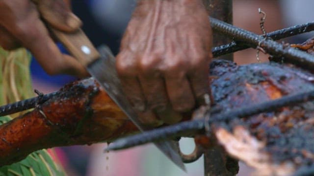 Grilled whole pig barbecue being sliced outdoors