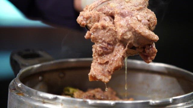 Gloved hands handling cooked meat