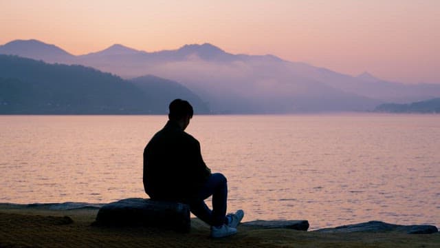 Contemplative Man at Lakeside during Sunset