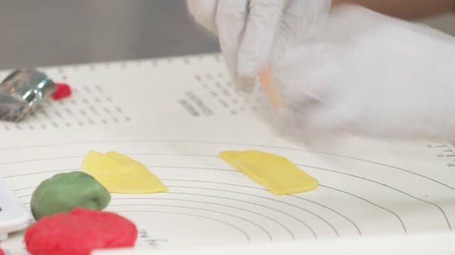 Hands preparing colorful dough pieces on a table