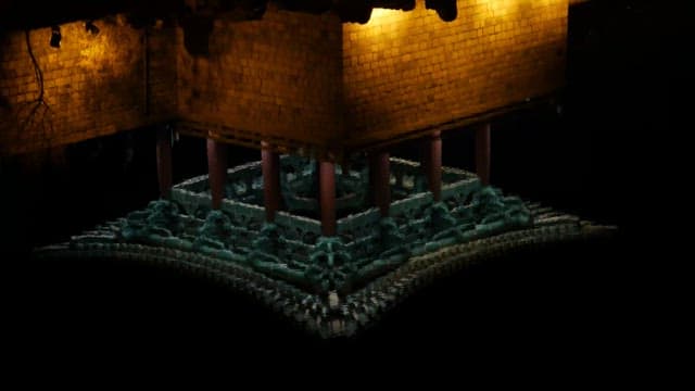 Night view of a pavilion illuminated with yellow lights, surrounded by trees