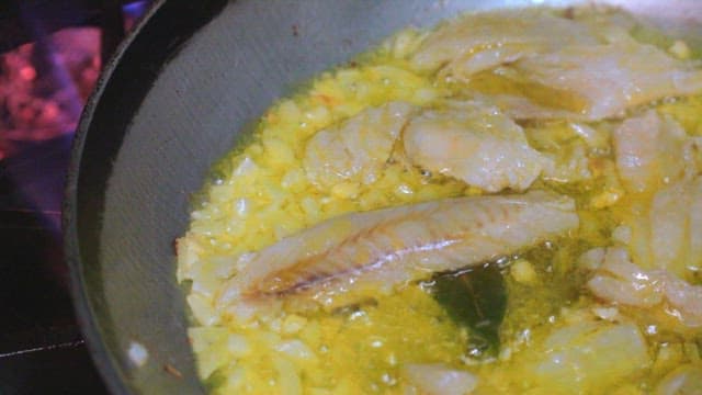 Fish fillets with garlic cooked in a hot oiled pan