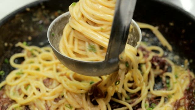 Creamy pasta rolled with chopsticks on a ladle