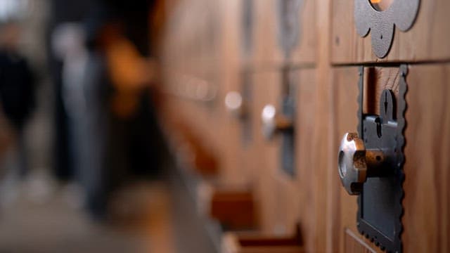 In front of a wooden locker with people crowding around