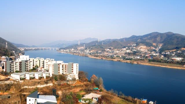Riverside Cityscape with Mountains and Clear Sky