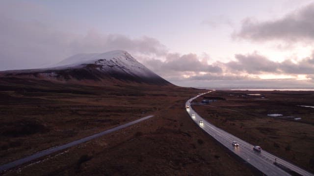 Winding road by a snowy mountain at dusk