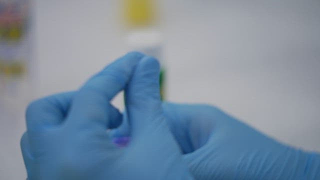 Scientist wearing blue gloves working on a sample