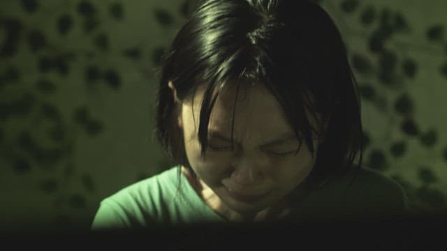 Sad girl crying bitterly in a dark room