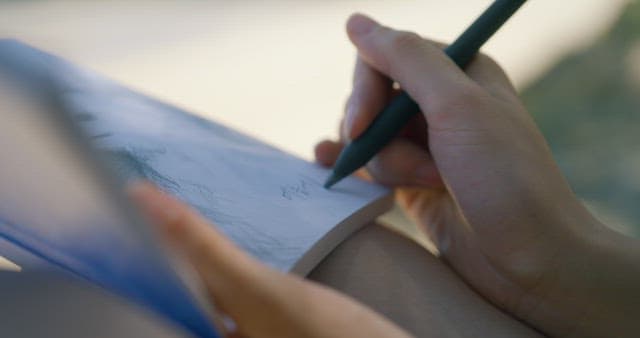 Person sketching in a notebook outdoors