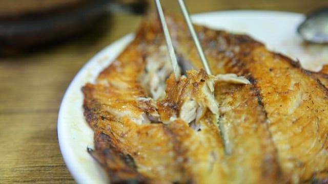 Grilled mackerel being flaked with chopsticks
