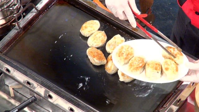 Crispy fried dumplings being cooked on a griddle