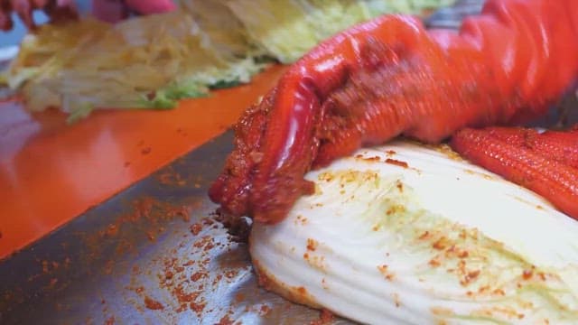 Making kimchi by adding chili pepper seasoning to cabbage