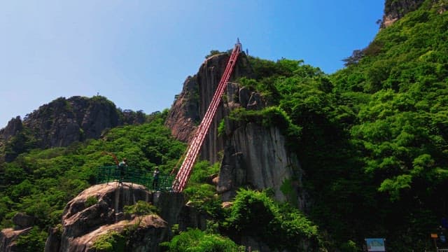 Red stairs and observation deck on a mountain covered with green trees