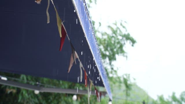 Rain falling on decorated awnings and light bulbs in the garden
