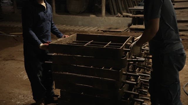 Workers handling metal frames in a factory