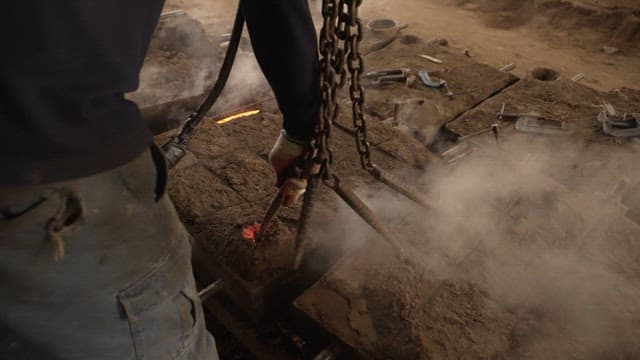 Worker handling hot metal in a factory
