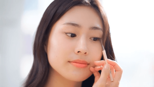 Woman applying eyeliner with concentration indoors